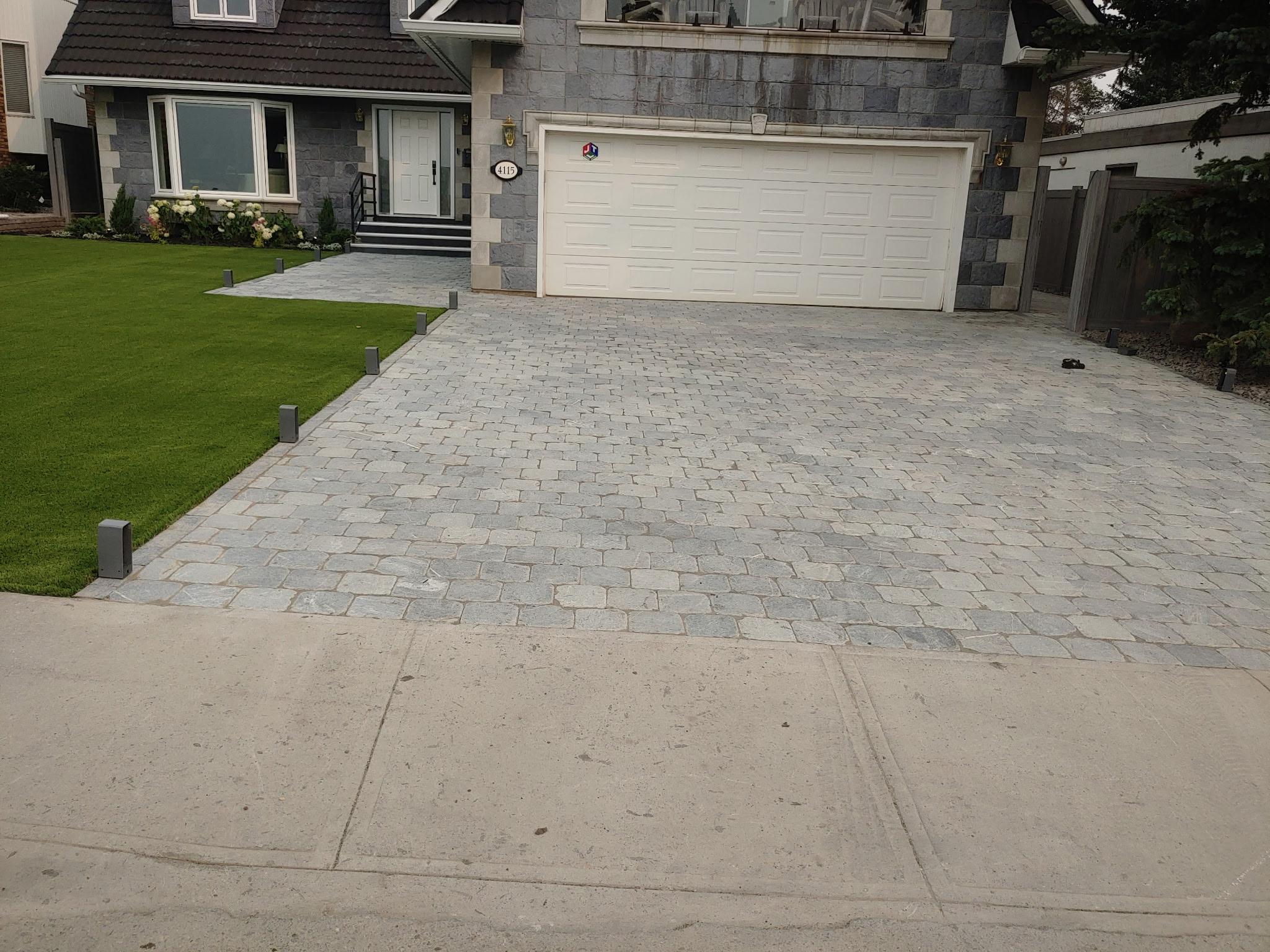 Wide cobblestone paver driveway in front of large home